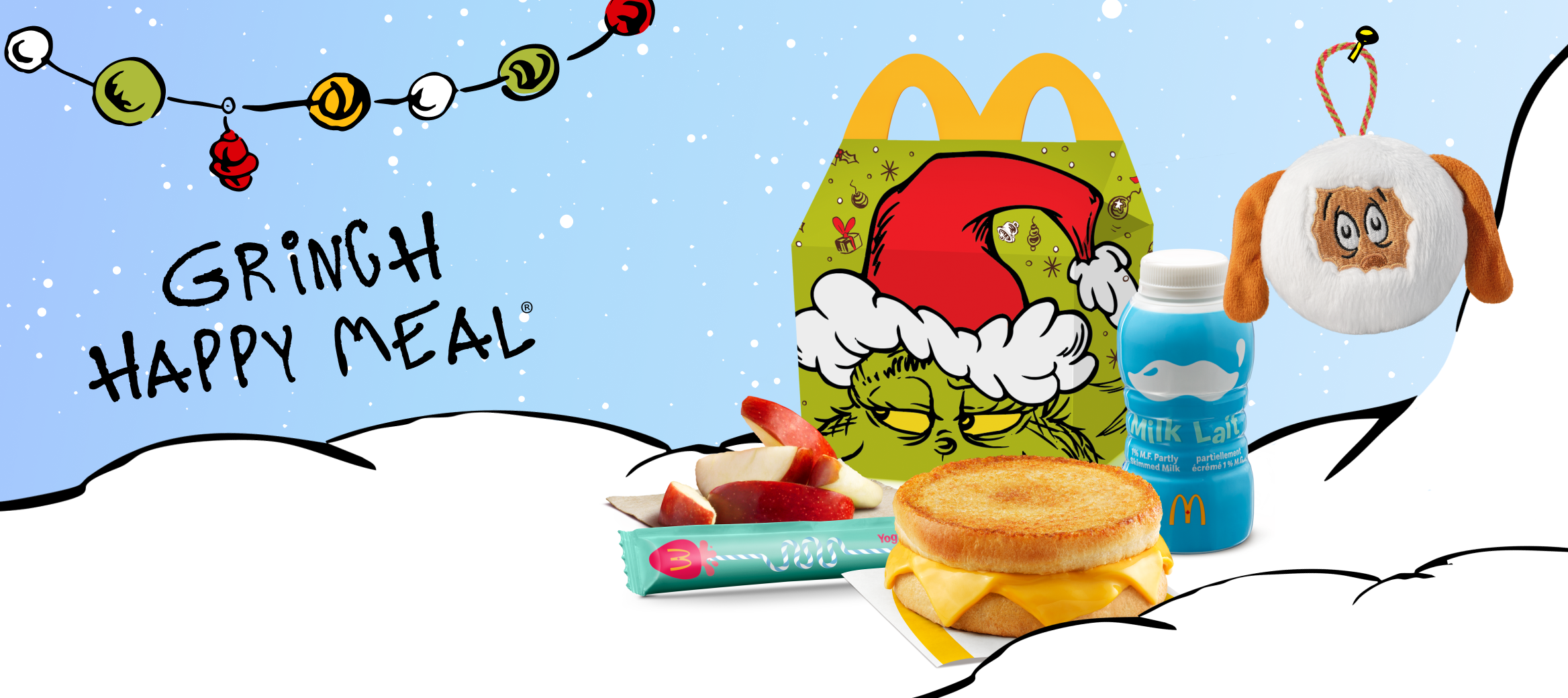 A Grinch Happy Meal® Box, Apple Slices, a Bottle of Milk, a Grilled Cheese Sandwich, and a Grinch Themed Christmas Ornament taped next to the words “Grinch Happy Meal”.