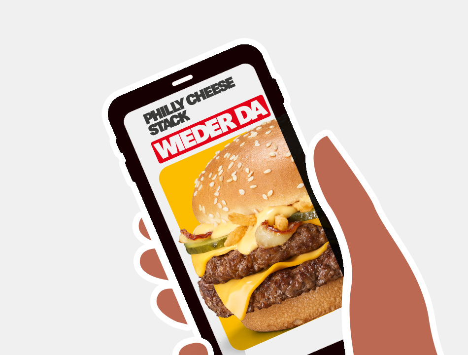Eine Hand hält ein Smartphone hoch, auf dessen Screen der wiedergekehrte Philly Cheese Stack gezeigt wird.