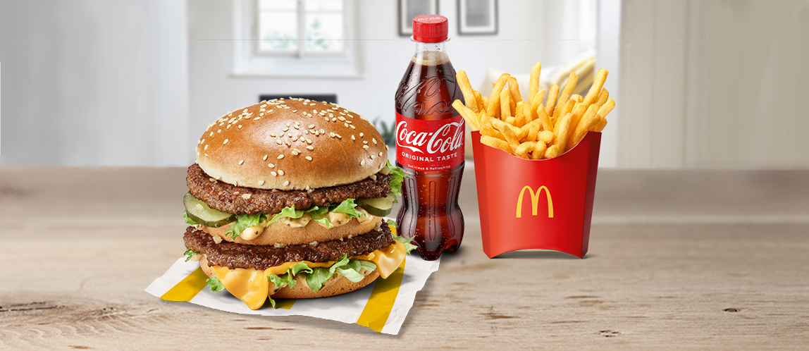 Auf dem Bild befindet sich ein saftiger Burger, eine Flasche Coca Cola und einmal Pommes Frites groß.