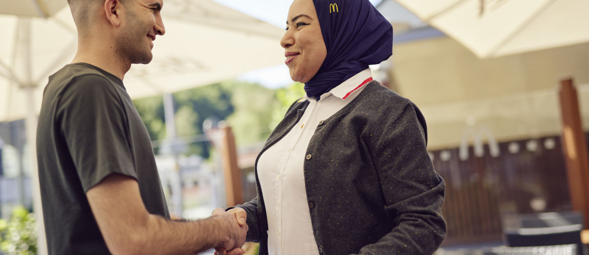 Junger Mann und McDonald’s Mitarbeiterin geben sich die Hand