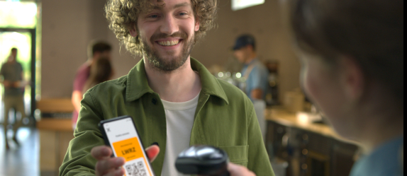 Ein Mann lässt an der Kasse den QR-Code auf seinem Handy scannen