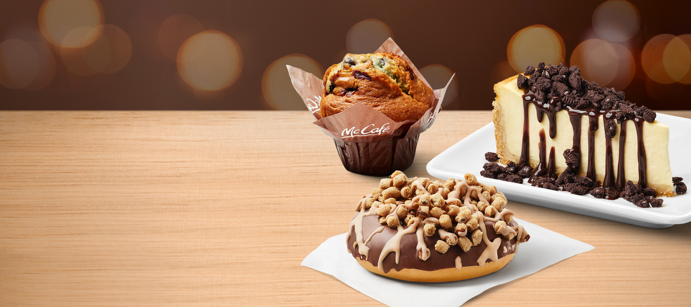 McCafé® Blaubeer Muffin, N.Y. Style Cheesecake mit OREO®-Topping und Schoko-Sauce und Cookie Dough Donut