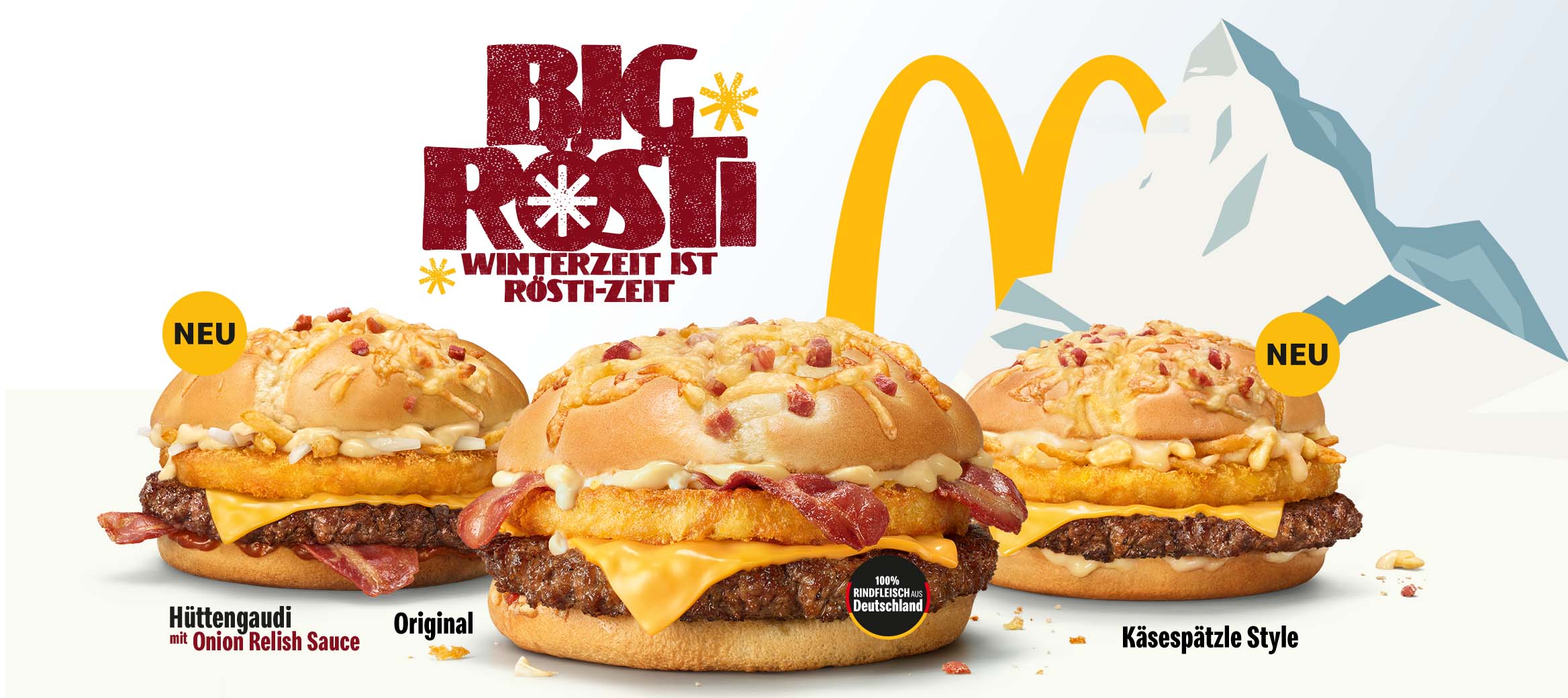 Wir sehen drei verschiedene Big Rösti vor einem schneebedeckten Berg.