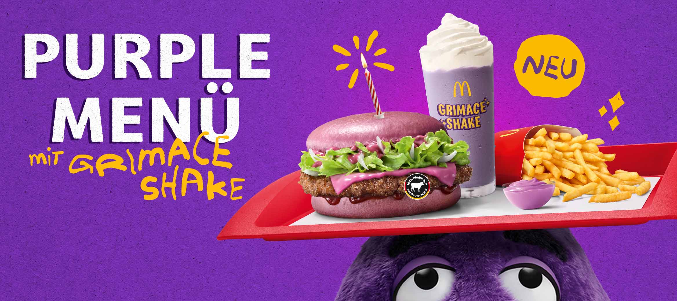 Links steht der Text "Purple Menü mit Grimace Shake", rechts kommt von unten der Kopf von Grimace ins Bild, auf seinem Kopf balanciert er ein Tablet mit einem Purple BBQ, einem Grimace Shake, Pommes und dem Purple Berry & Cream Dip; alles auf lila Hintergrund.