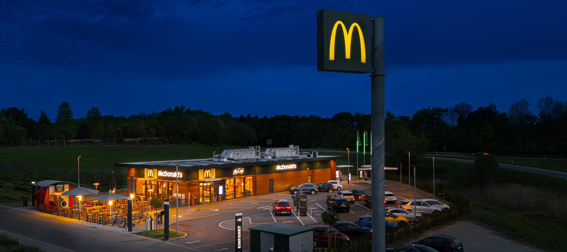 Beleuchtetes McDonald’s Restaurant mit Parkplatz bei Nacht