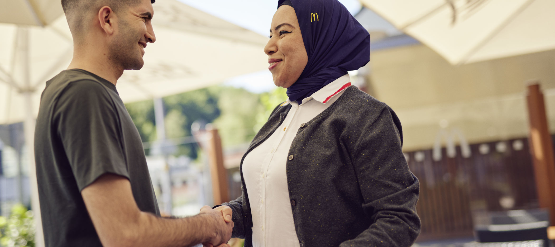 Junger Mann und McDonald’s Mitarbeiterin geben sich die Hand