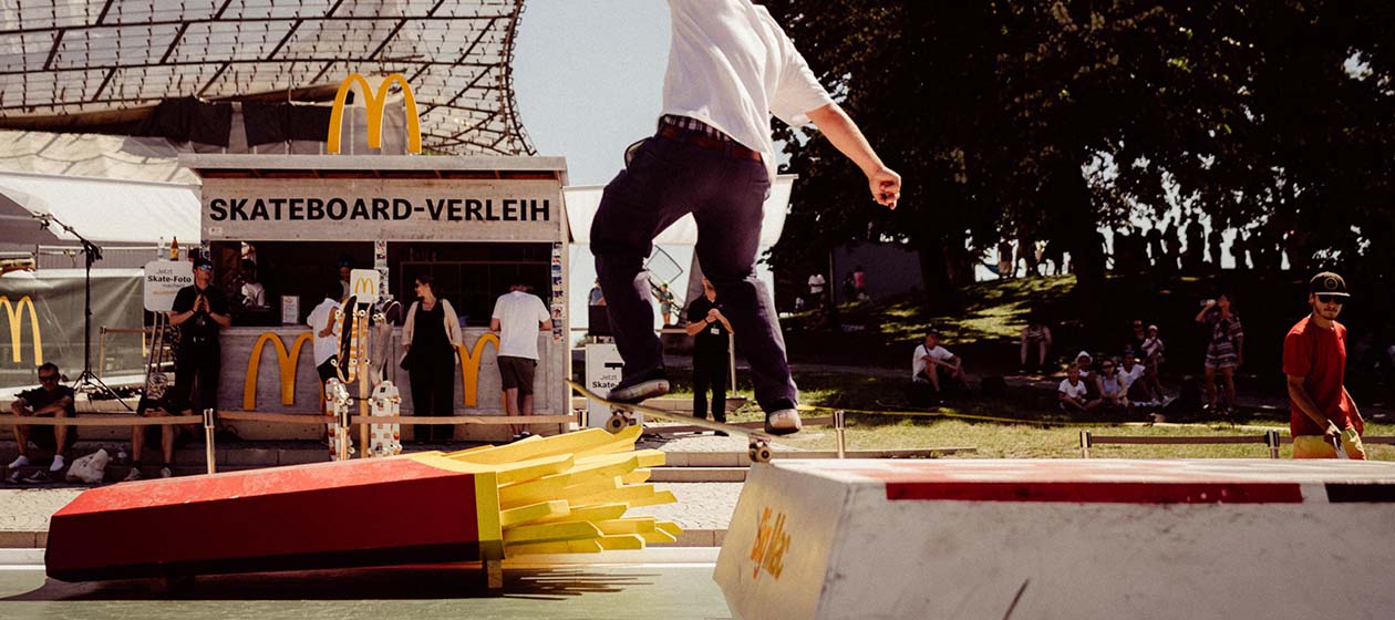 Skateboardfahrer in Skatepark mit Hindernissen in Form von McDonald's Produkten