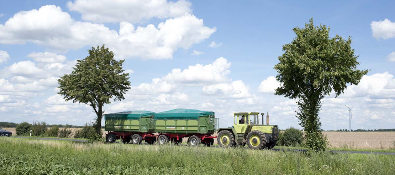 Traktor mit zwei Anhängern auf einer Landstraße