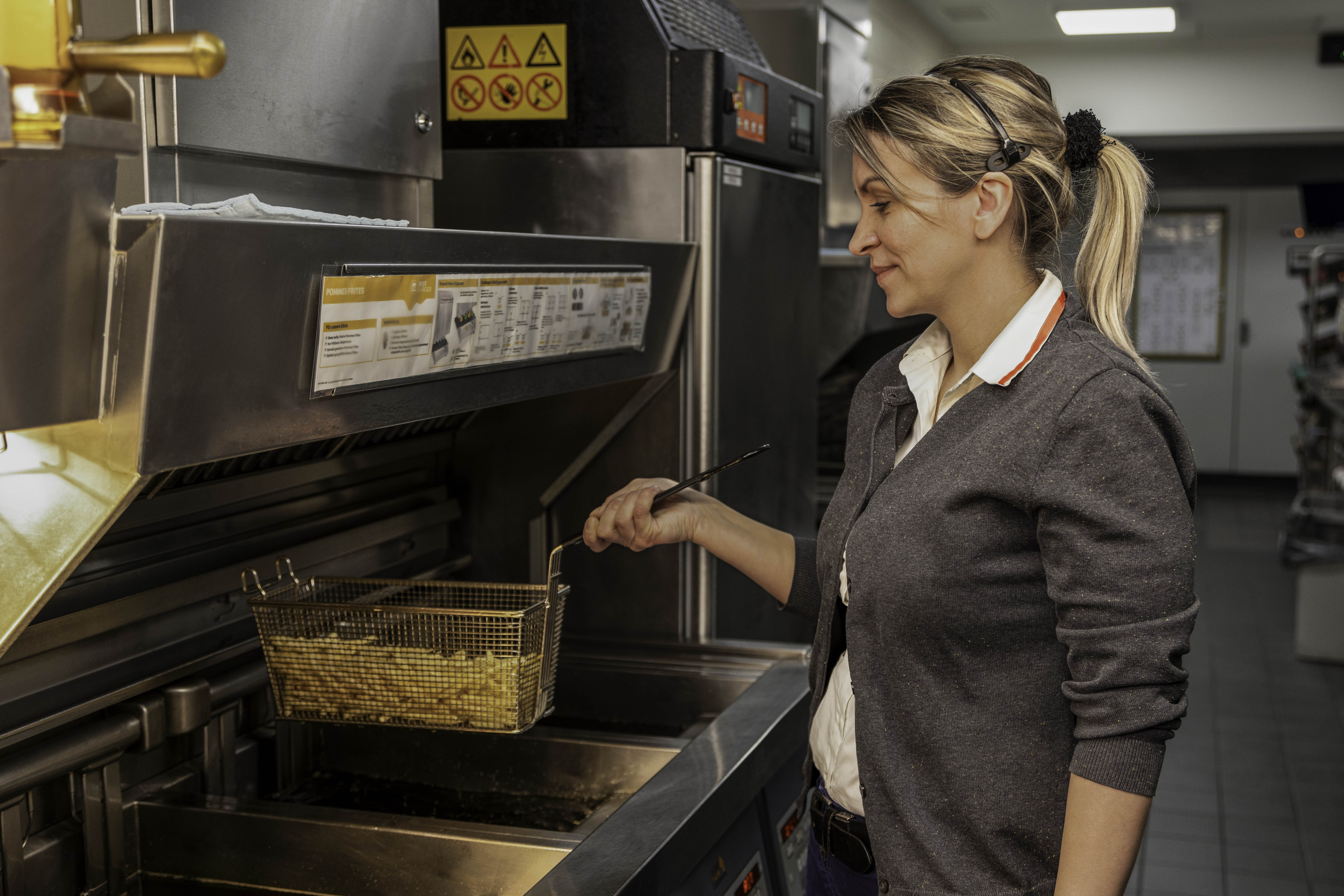 Mitarbeiterin arbeitet an Pommesfritteuse