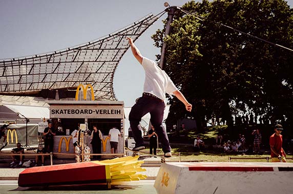 Skateboardfahrer in Skatepark mit Hindernissen in Form von McDonald's Produkten