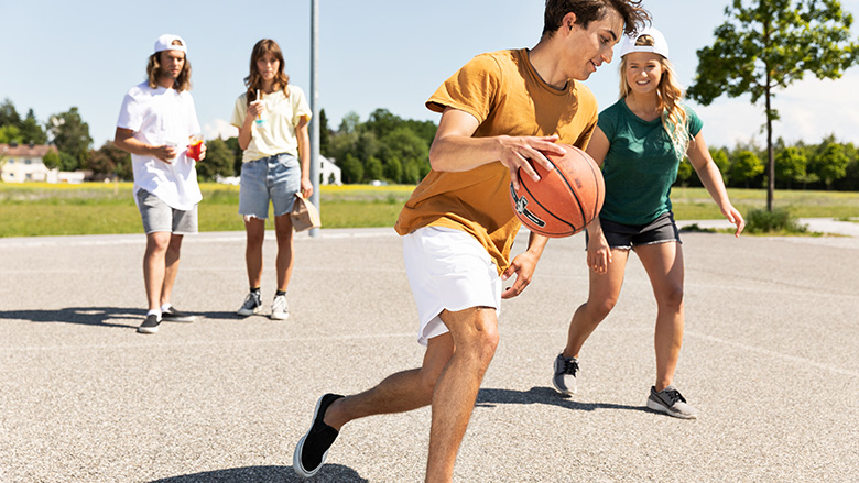 Jugendliche spielen auf einem Steinplatz Basketball