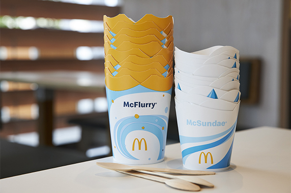 Holzlöffel vor gestapelten McFlurry®- und McSundae®-Bechern