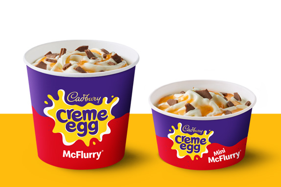 Regular and mini Cadbury Creme Egg McFlurry cups with chocolate pieces, shown on a yellow and white background.