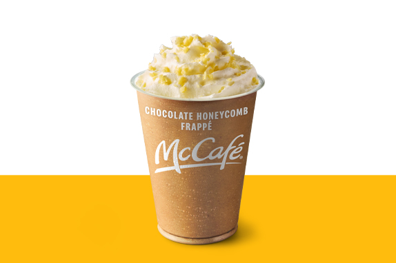 Chocolate Honeycomb Frappe topped with a swirl of whipped cream and honeycomb pieces set against a yellow and white background