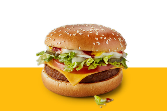 McPlant burger with plant based patty, lettuce, tomato, and sauce, shown on a yellow and white background.