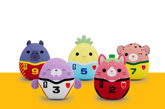 Five Squishmallows toys styled as football characters with numbers, including animal and fruit designs, arranged in a row.