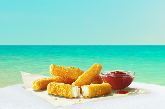 Halloumi fries and tomato dip on top of a table by the sea.