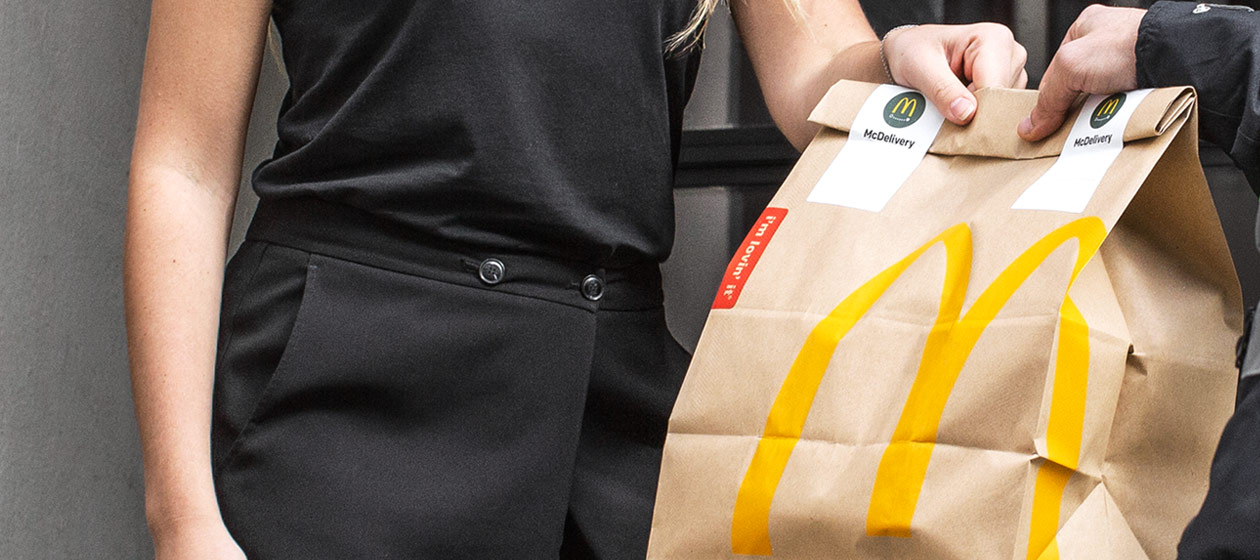 En kvinna tar emot en McDonald's påse som körts hem till henne med hemleverans.
