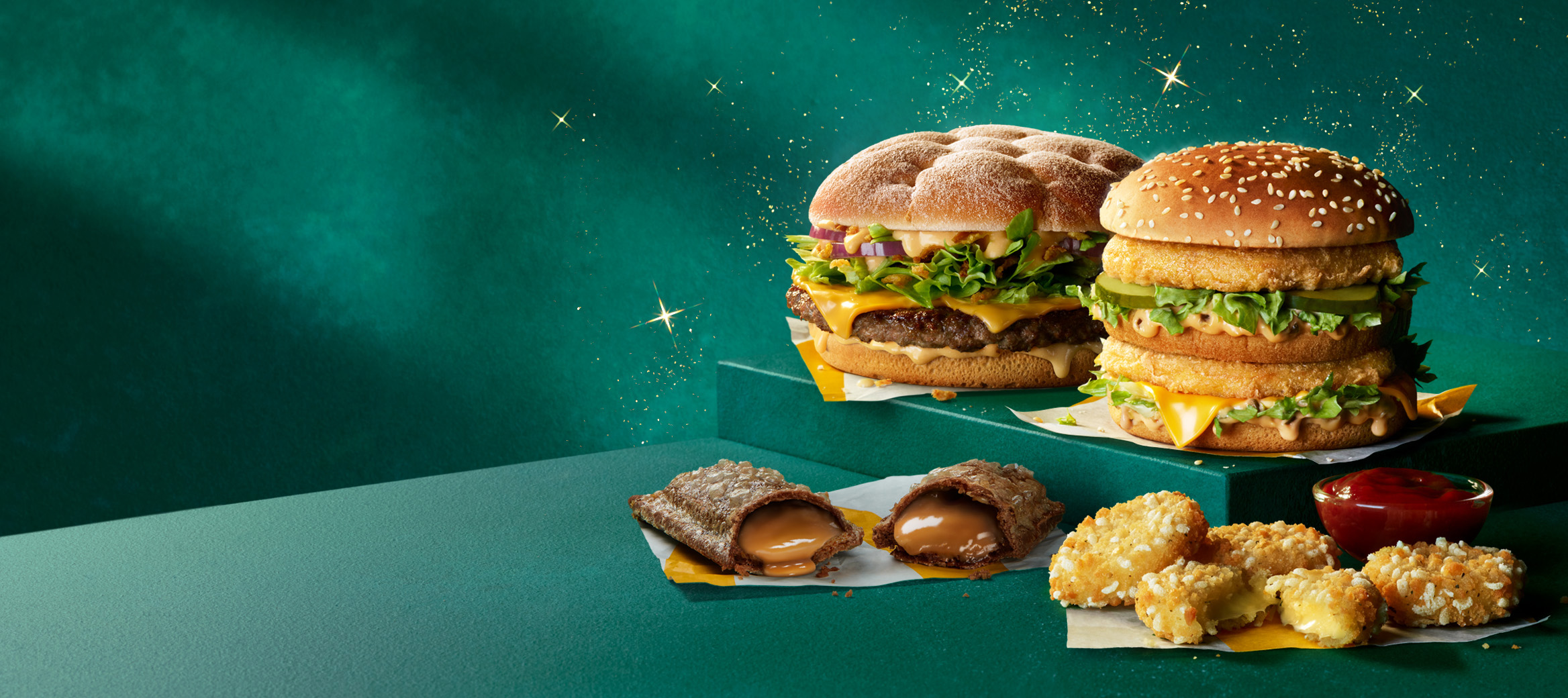 Two McDonald’s burgers, one caramel pie, cheese dippers and a sauce on a green plinth with a green starry background.