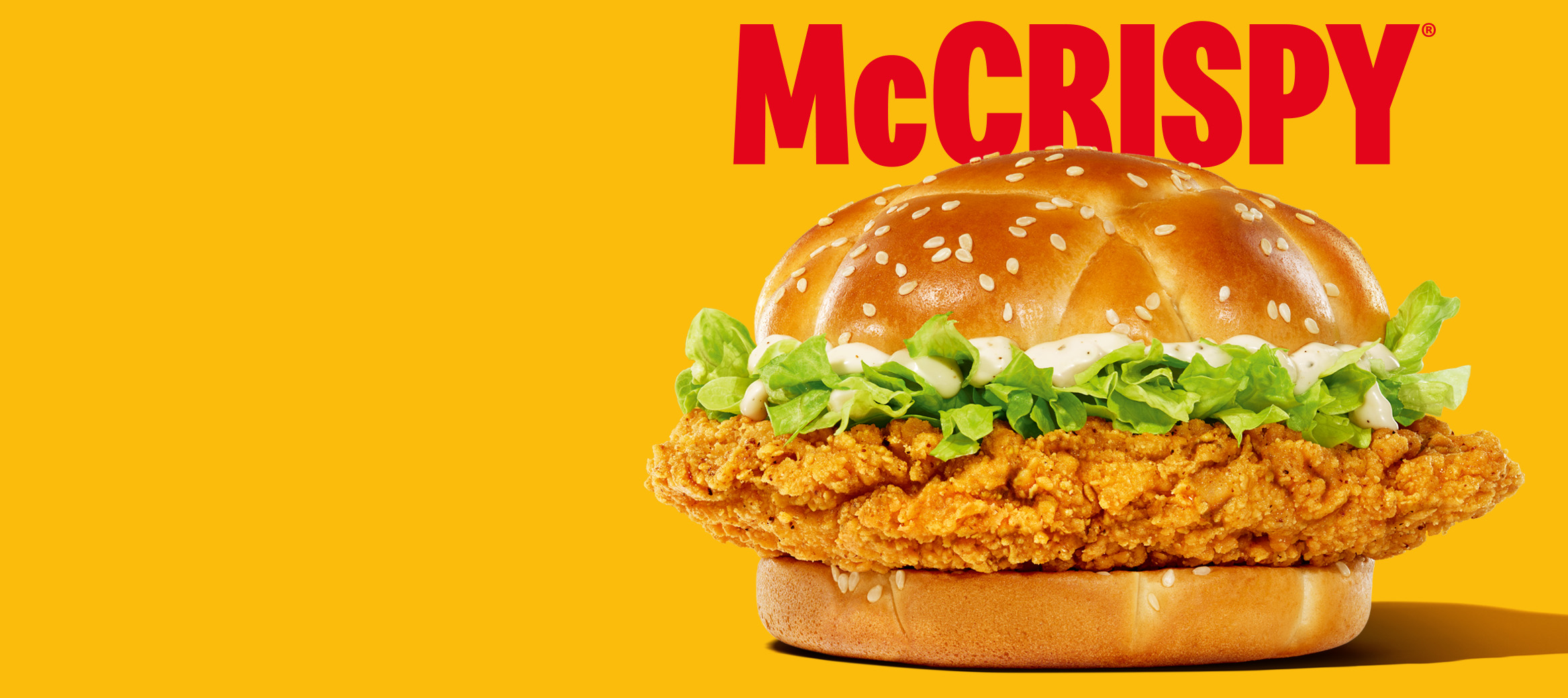 McCrispy burger on a plain yellow background with bold red font saying “McCrispy” above it. 