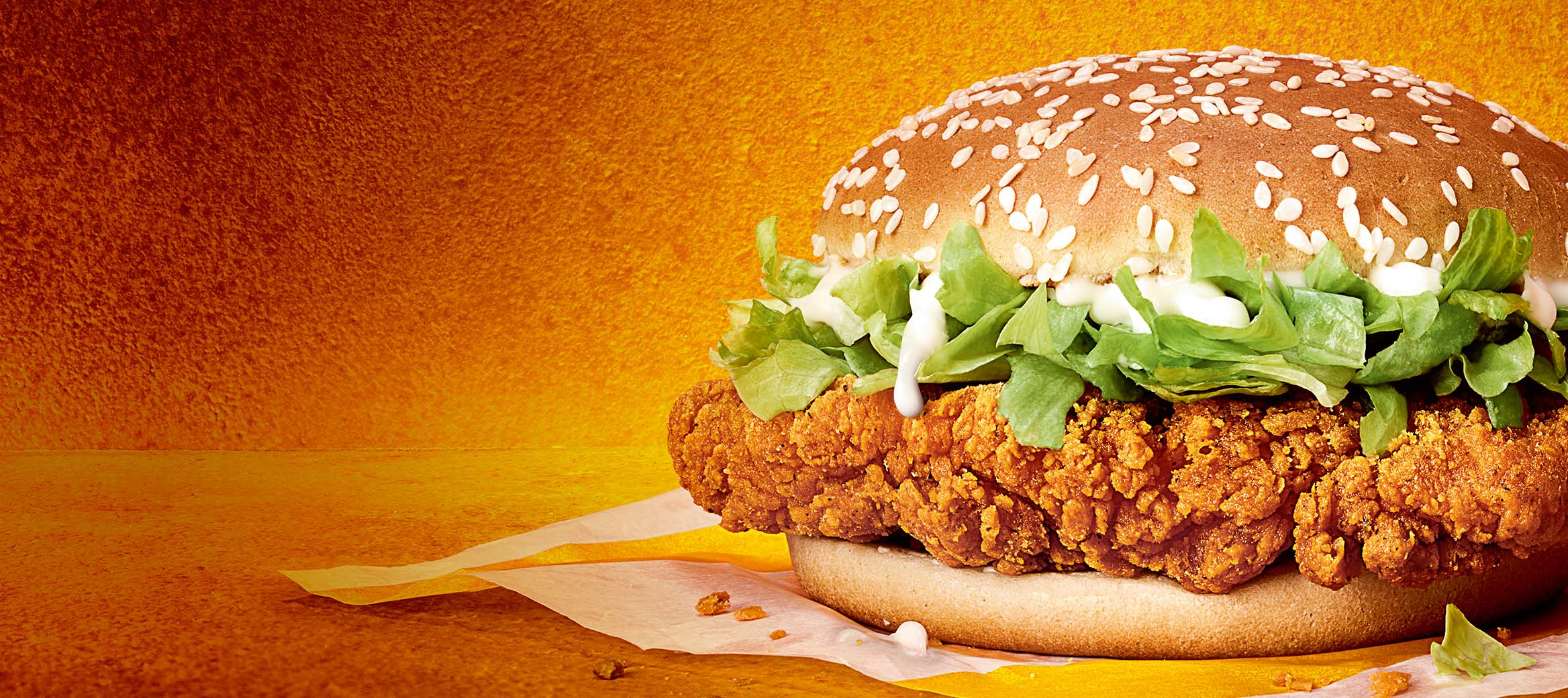 Crispy coated golden chicken breast, with crunchy lettuce and a creamy sauce, on a sesame seeded golden bun.