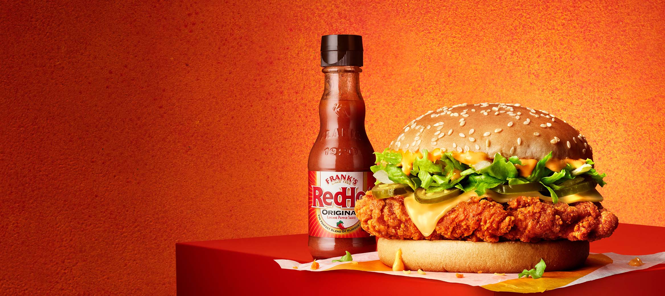 McSpicy Burger with the Franks Extra Hot  Sauce on a fiery, red-coloured background. 