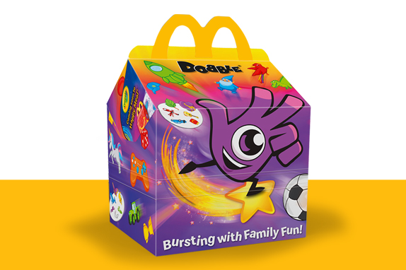 A brightly coloured McDonald’s Happy Meal box decorated with Dobbly and playful icons, set against a yellow and purple background.