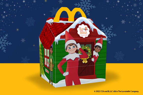 Happy Meal box as a gingerbread house with two Elf Mates on a yellow shelf and a snowy, blue background.