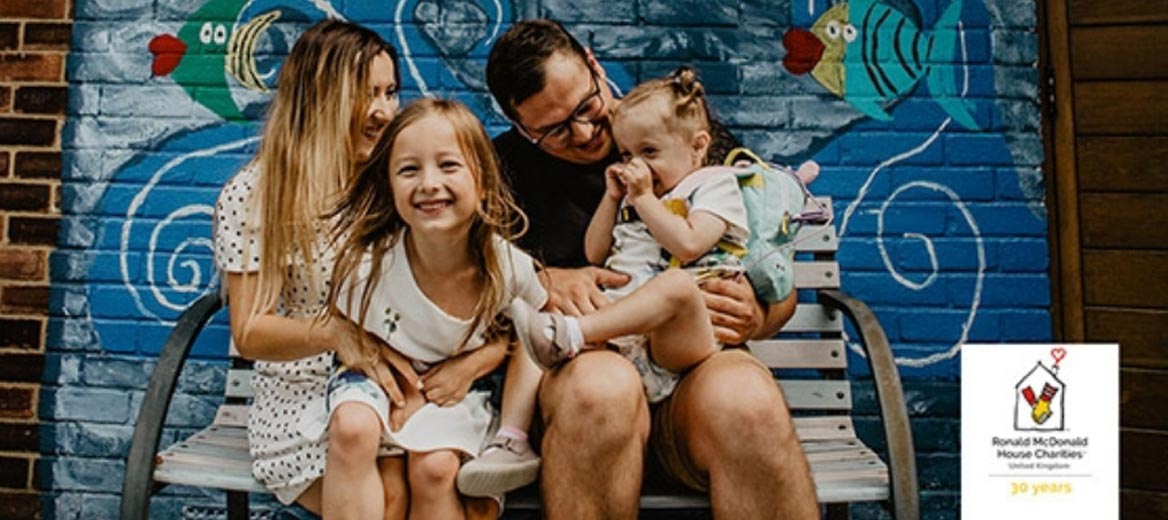 Family sitting on a bench in front of a mural.