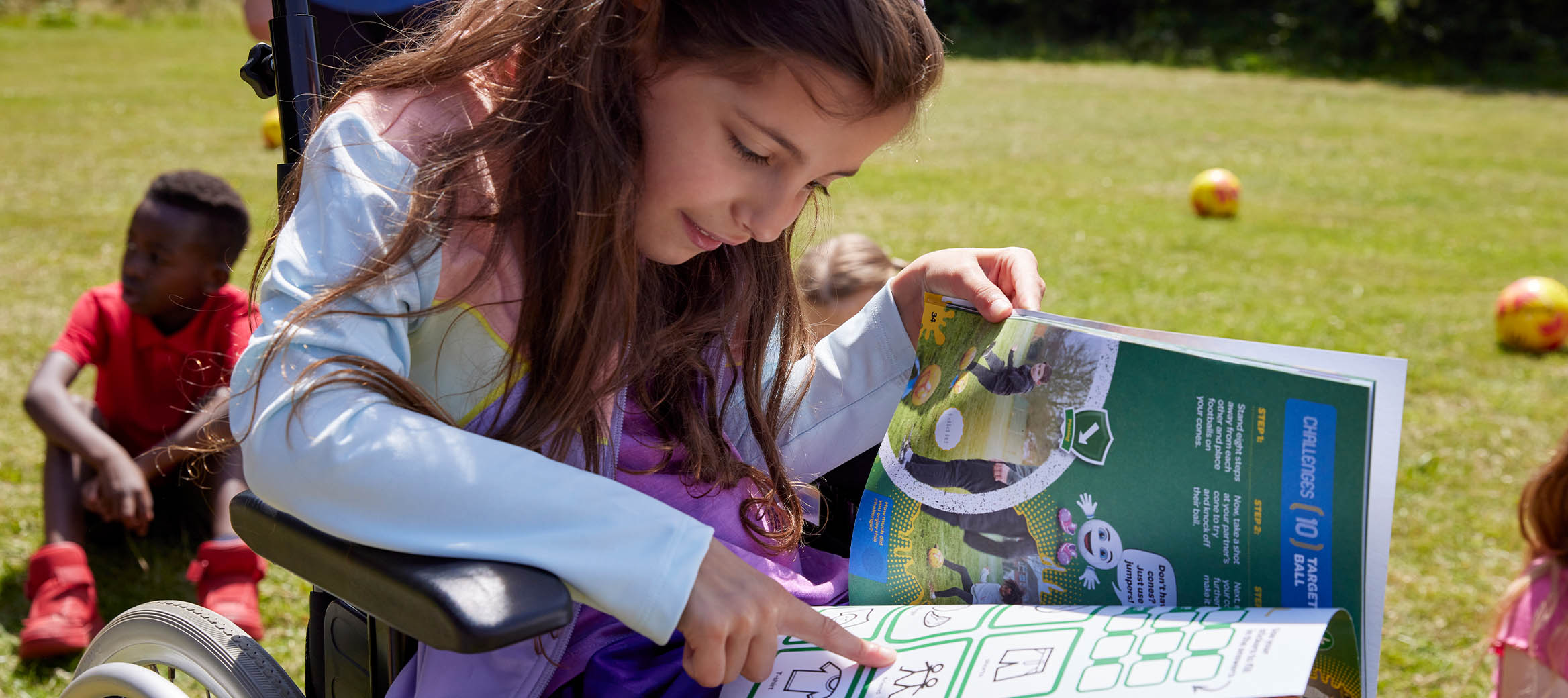 Group of young kids sitting around a football coach handing out fun football activity book