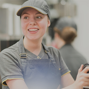 A young restaurant worker is smiling whilst on shift.