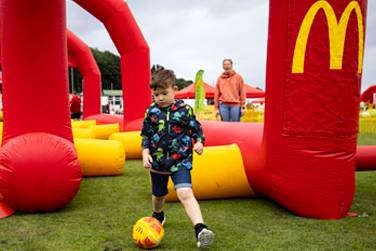 Fun Football coach supervising children playing football.