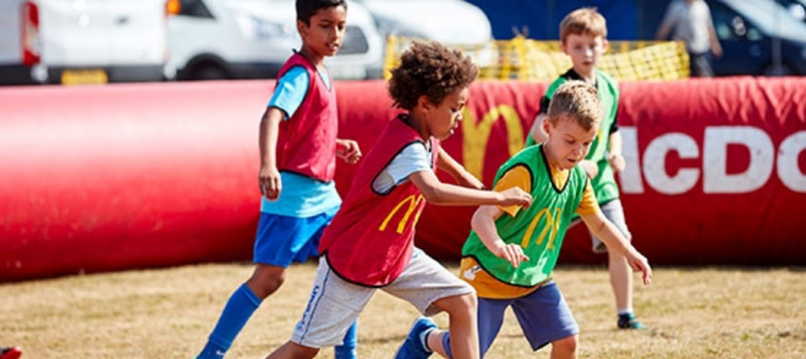 Children having fun and playing football in brightly coloured bibs.