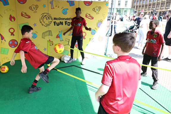 Keira Walsh and child playing football with illustrations of paint brushes and canvas.