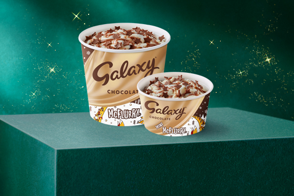 Two chocolate McDonald’s brown ice cream cups on a green plinth with a starry background.