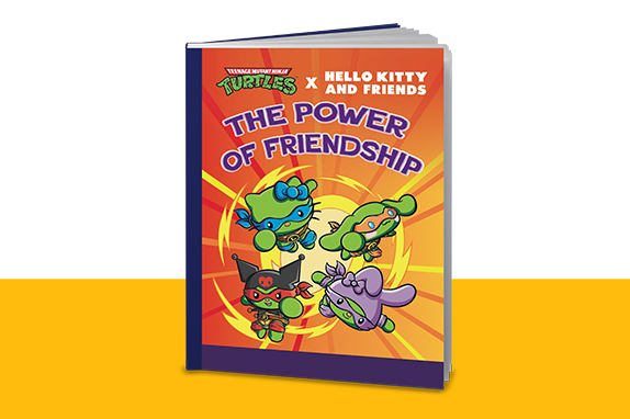 Book titled “The Power of Friendship” featuring Teenage Mutant Ninja Turtles x Hello Kitty and Friends characters on a bright orange and yellow background. The cover shows four colorful cartoon characters with masks and accessories.