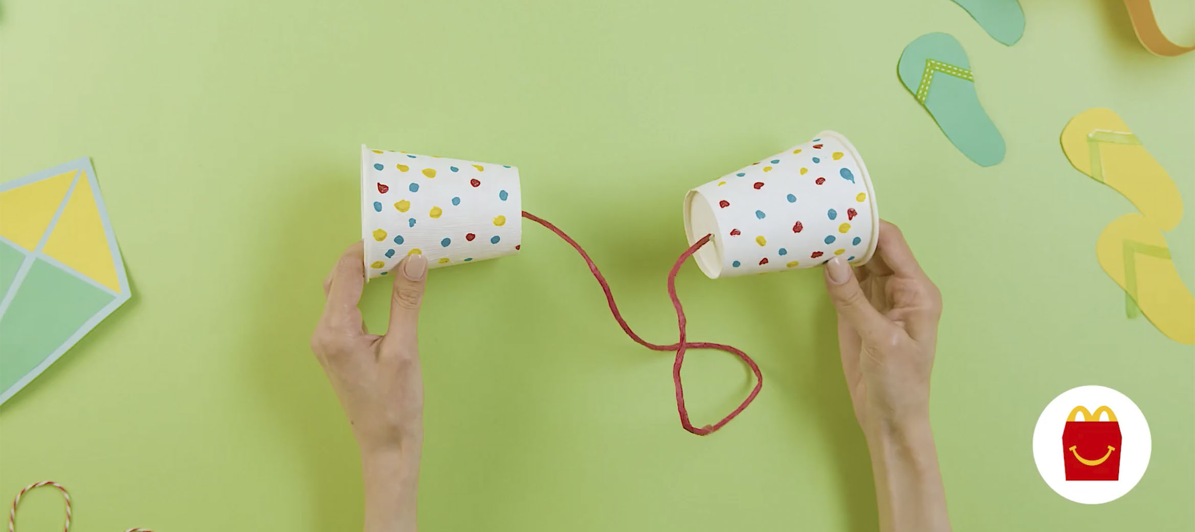 Hands holding a paper cup telephone.