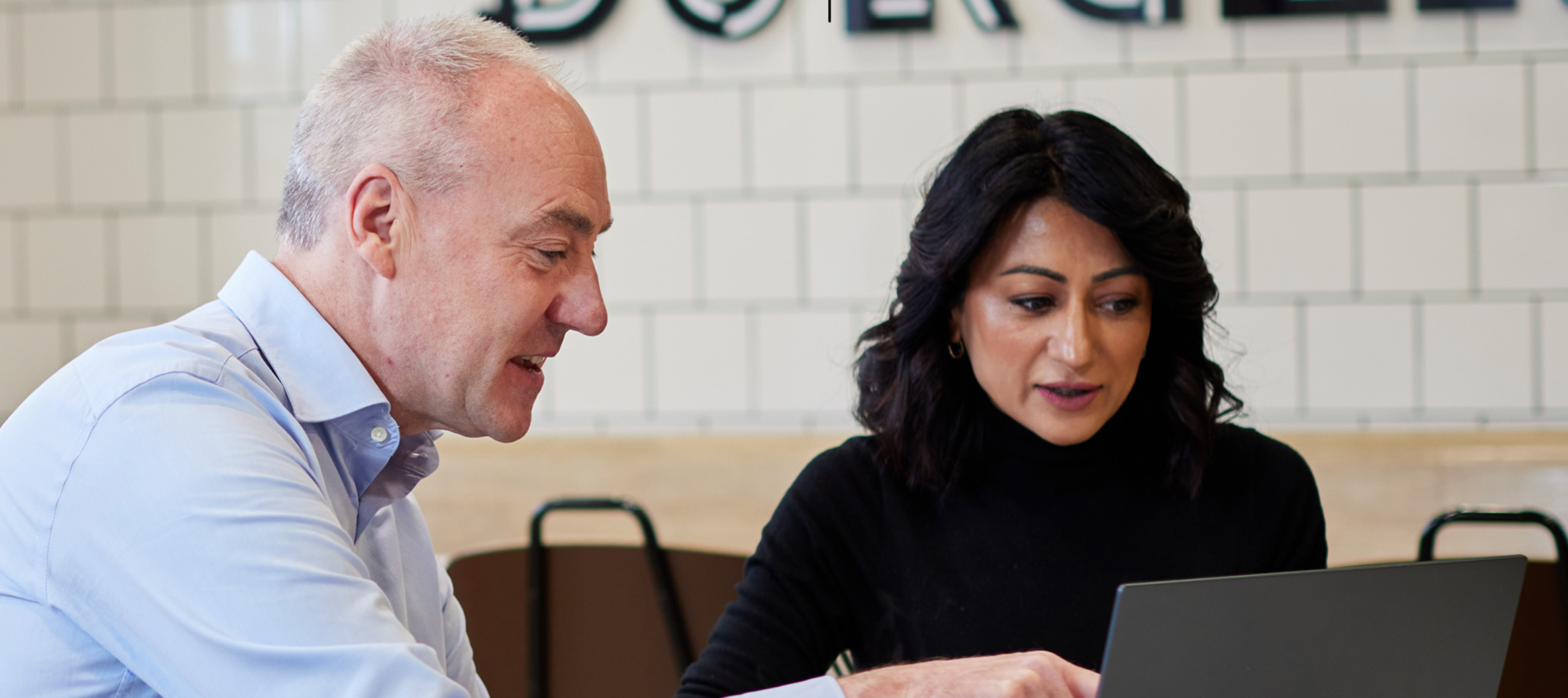Franchise Consultant reviewing performance data on a laptop with multi-site franchisee Anisha Sharma.