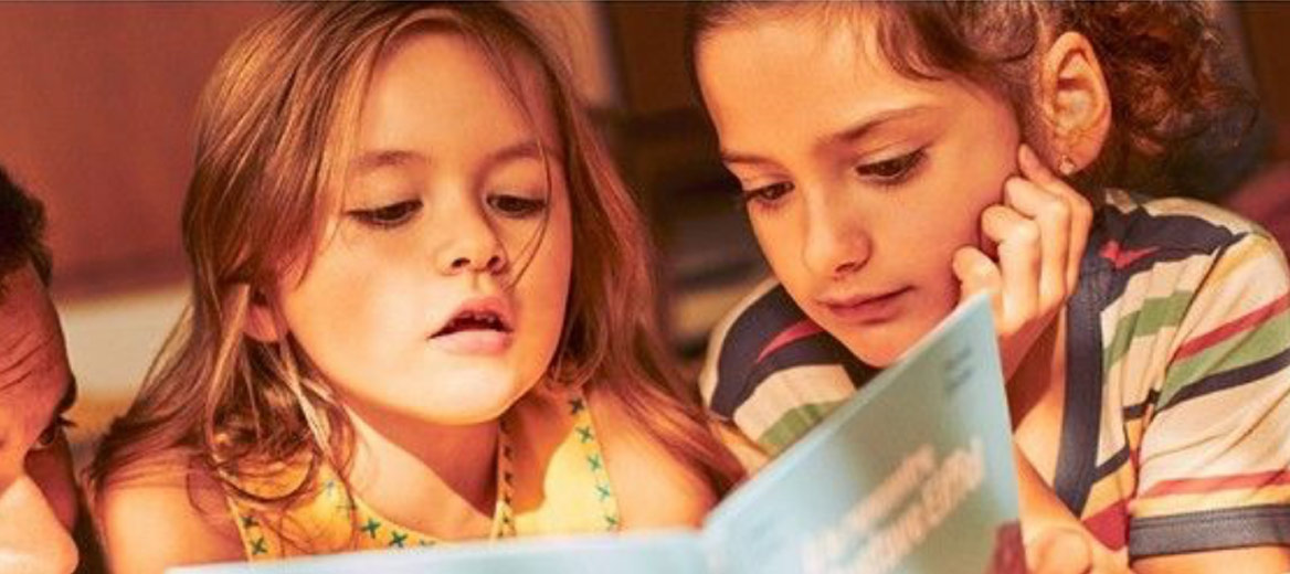 Two children reading a book together.