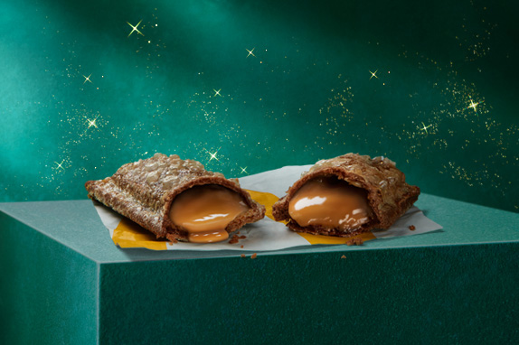 A caramel pie on a green plinth with a green starry background.