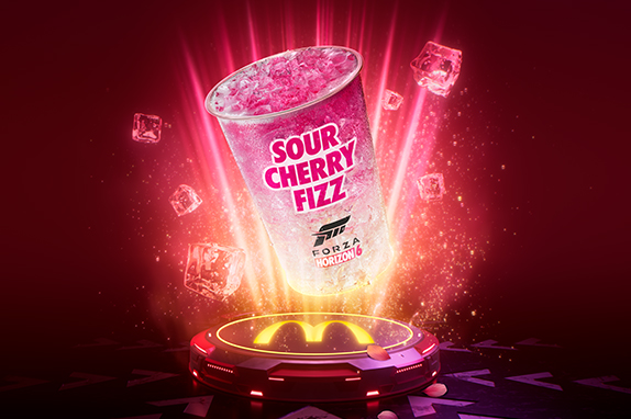 Large Sour Cherry Fizz drink with Forza Horizon 6 branding floating above a glowing McDonald's platform, surrounded by sparkling ice cubes against a vibrant red background.