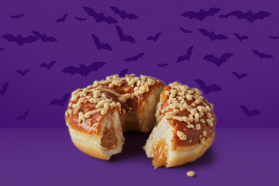 A purple background with bats flying and a donut.
